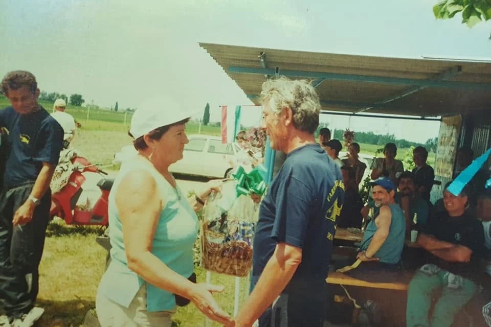 Régi felvétel: díjátadás a tó melletti büfénél, a háttérben padokon ülő horgászokkal.
